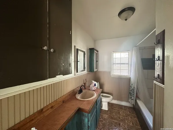 a bathroom with a granite countertop sink a toilet a mirror and shower