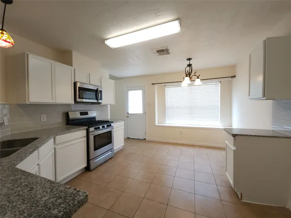 a kitchen with stainless steel appliances a white stove top oven cabinets and a window