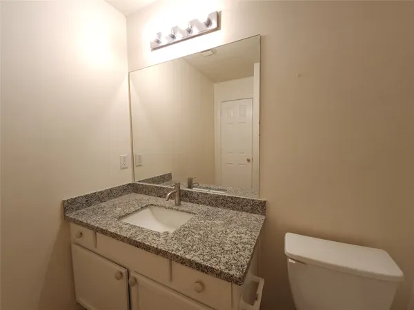 a bathroom with a granite countertop sink and a toilet
