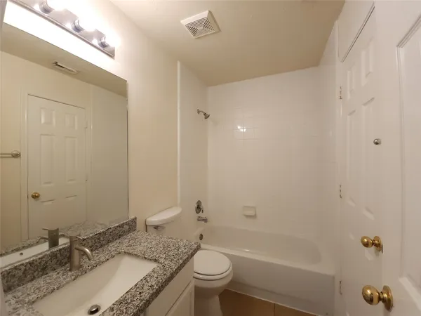 a bathroom with a granite countertop sink a toilet and shower