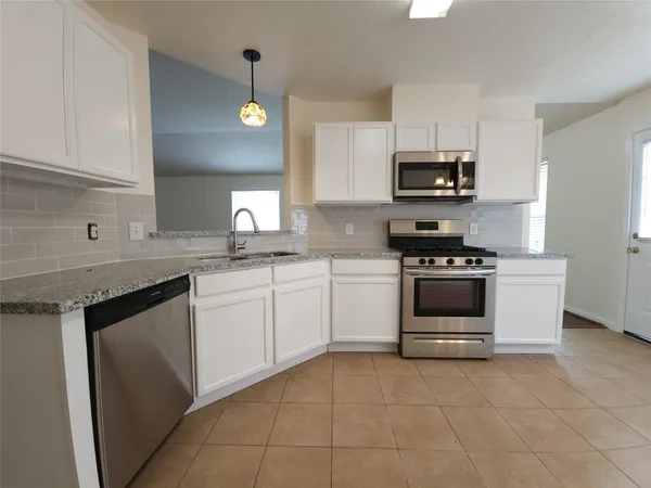 a kitchen with stainless steel appliances granite countertop a sink and dishwasher a stove top oven with white cabinets