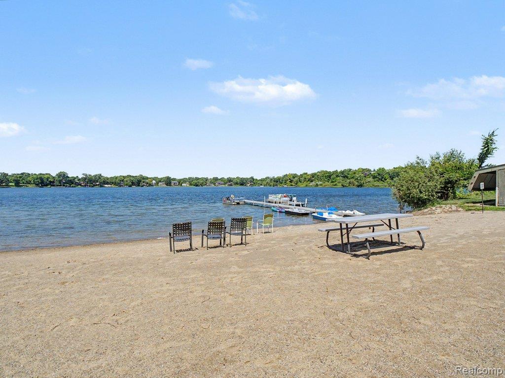 1974 Klingensmith Road, Unit 4 Bloomfield Hills, MI 48302 - Photo 28 of 35 Sandy shoreline with direct lake access featuring a private dock system, multiple watercraft, and an adjacent picnic area