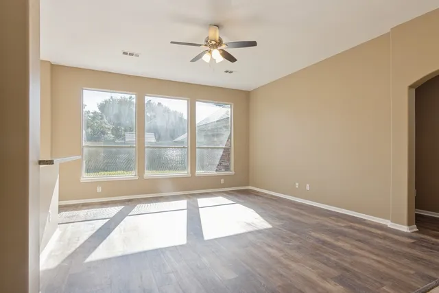 an empty room with wooden floor and windows