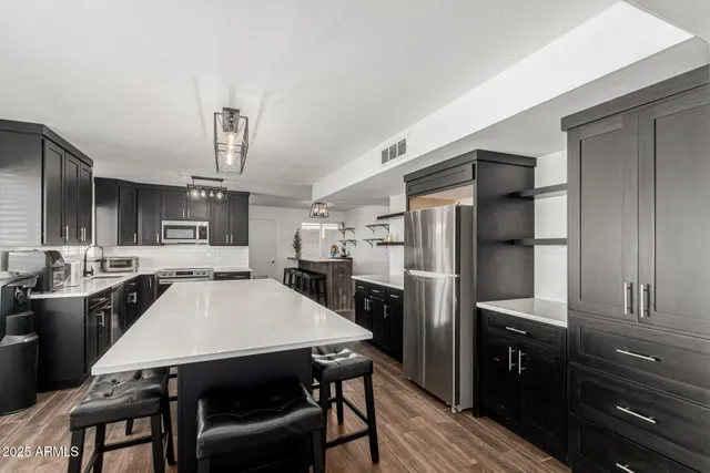 a kitchen with stainless steel appliances a refrigerator a stove a sink a dining table and chairs