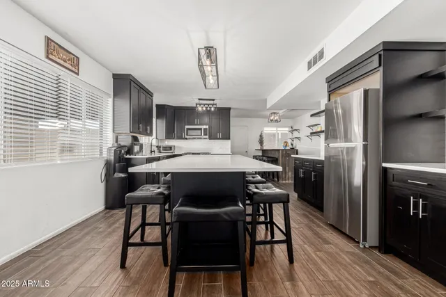 a kitchen with stainless steel appliances a dining table chairs refrigerator and cabinets