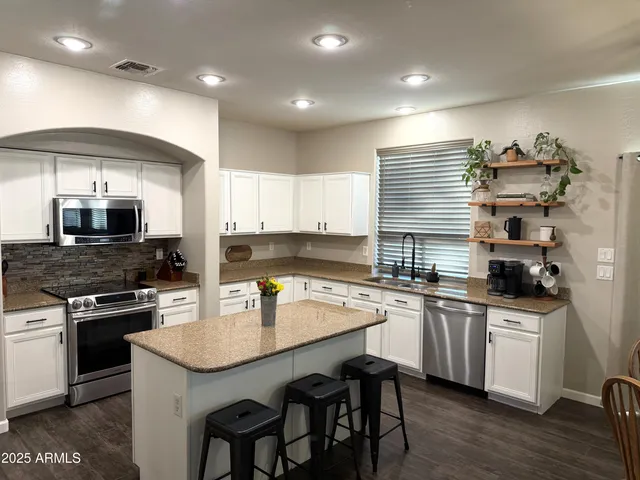 a kitchen with sink a refrigerator and chairs