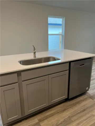 a kitchen with a sink and wooden floor