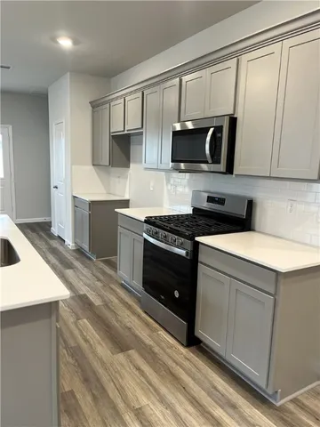 a kitchen with stainless steel appliances a sink a stove a microwave a sink and cabinets