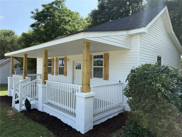 a view of a white house with a small yard and deck