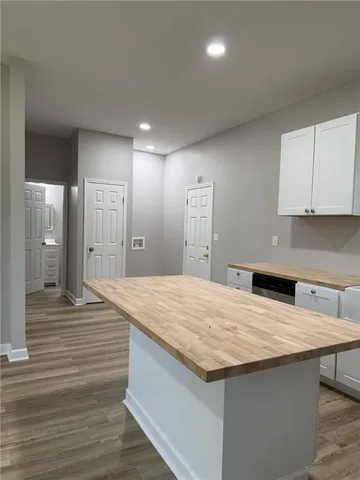 a room with kitchen island a sink wooden floor and glass door