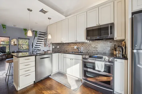 a kitchen with granite countertop a refrigerator stove and microwave