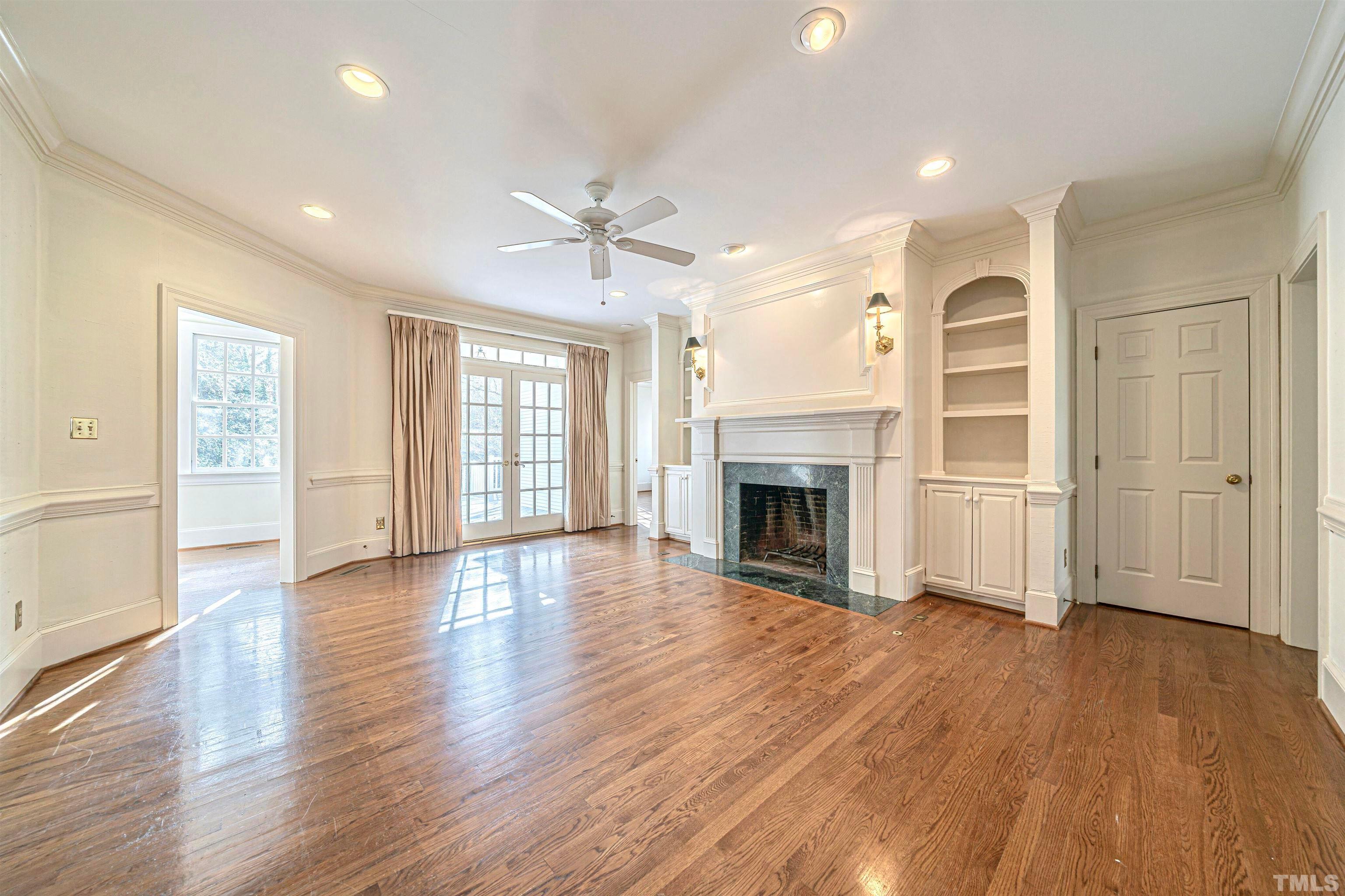 709 Runnymede Road Raleigh, NC 27607 - Photo 13 of 50 an empty room with wooden floor fireplace and windows
