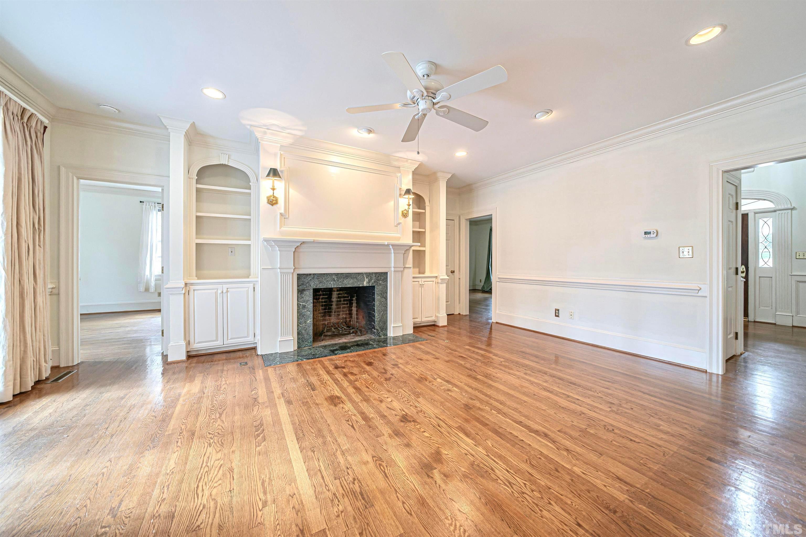 709 Runnymede Road Raleigh, NC 27607 - Photo 15 of 50 an empty room with wooden floor fireplace and windows