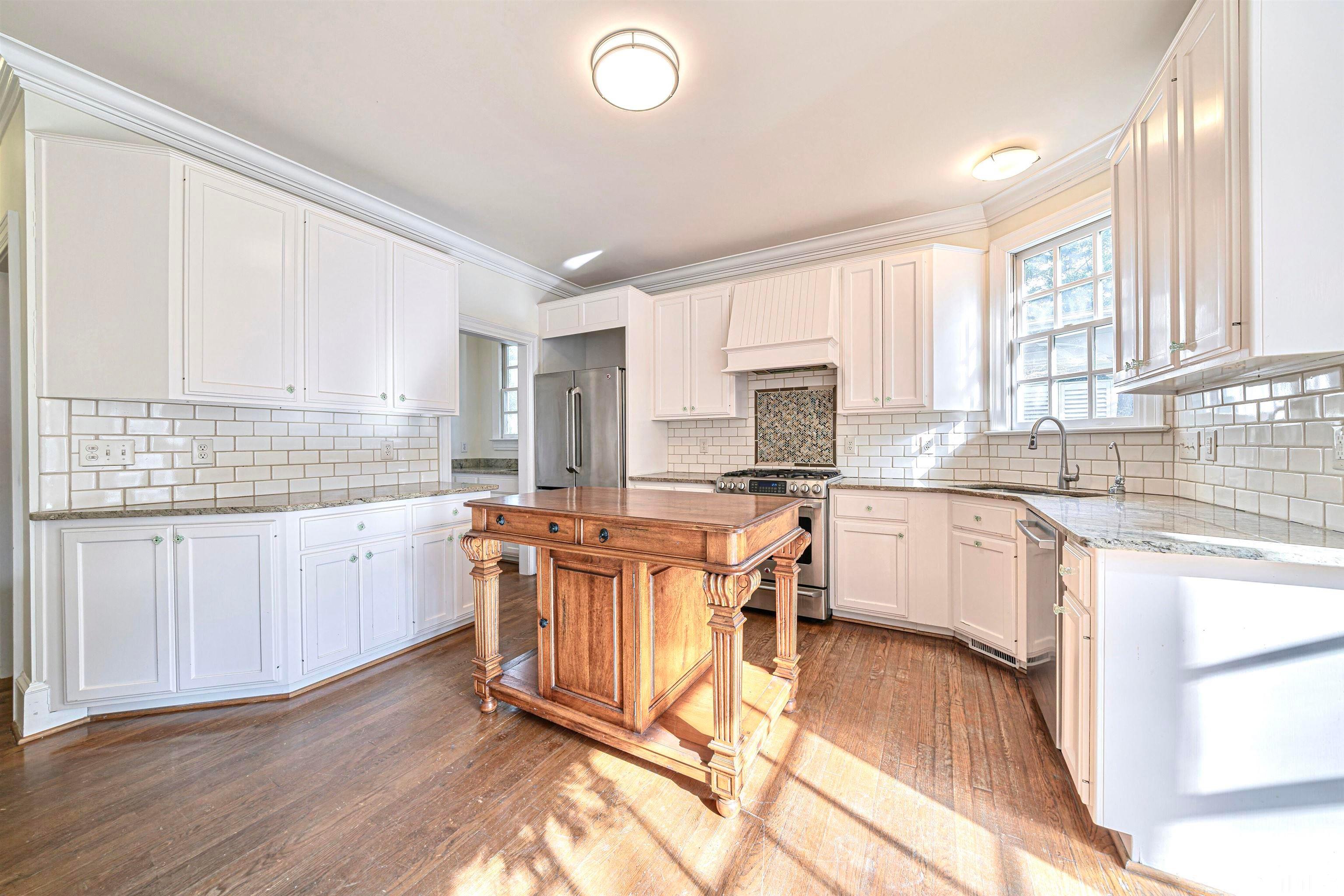 709 Runnymede Road Raleigh, NC 27607 - Photo 20 of 50 a kitchen with stainless steel appliances granite countertop a stove a sink dishwasher a refrigerator and white cabinets with wooden floor