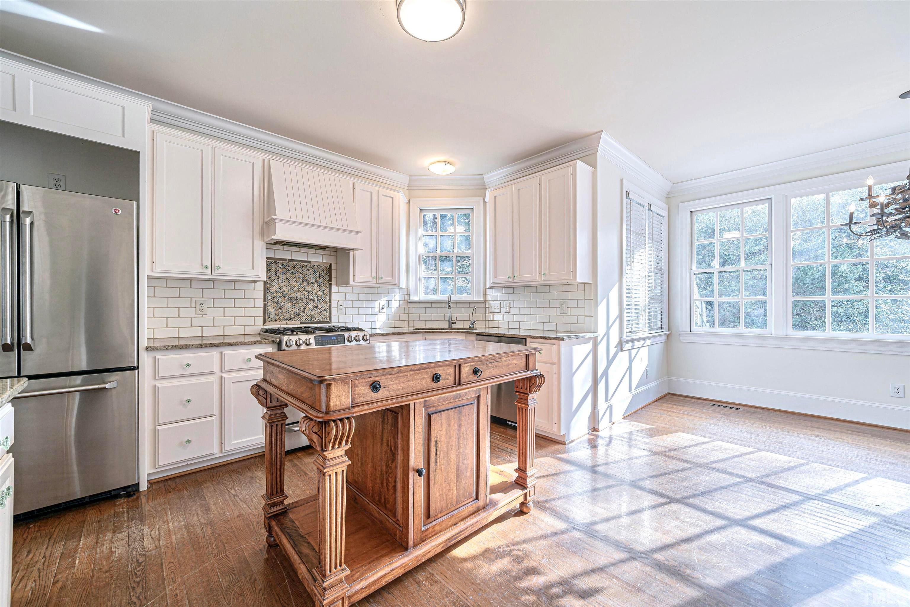 709 Runnymede Road Raleigh, NC 27607 - Photo 21 of 50 a kitchen with stainless steel appliances granite countertop a stove a sink dishwasher a refrigerator and white cabinets with wooden floor