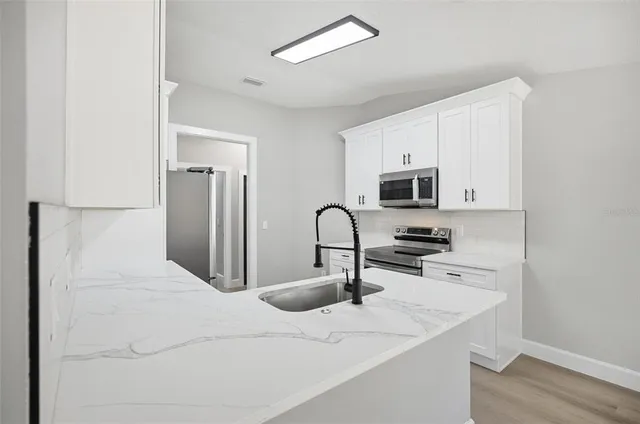 a kitchen with white cabinets appliances and a window