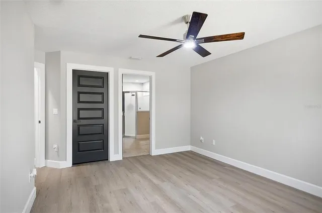 an empty room with wooden floor ceiling fan and windows