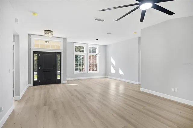 a view of an empty room with a window and wooden floor