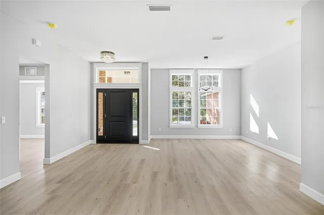 a view of an empty room with a window and wooden floor
