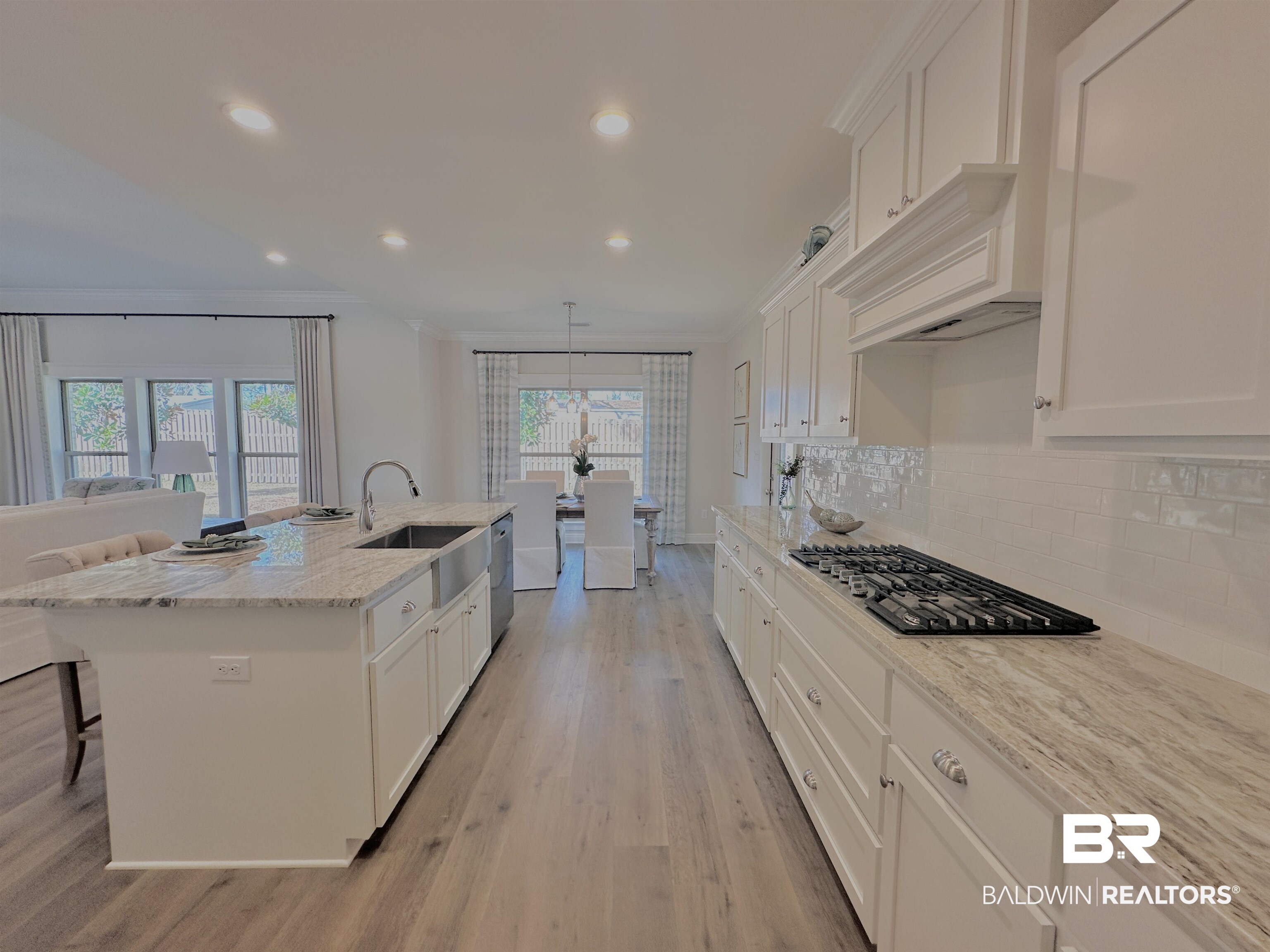 691 Kitfox Avenue Fairhope, AL 36532 - Photo 4 of 42 Kitchen with sink, light stone counters, tasteful backsplash, decorative light fixtures, and an island with sink