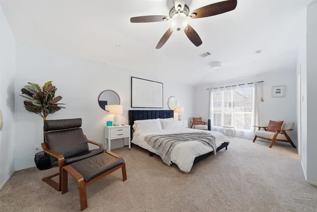 a bedroom with a bed a couch and a chandelier fan