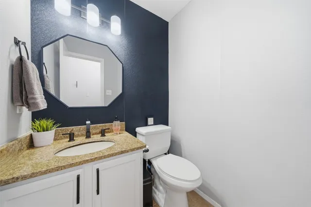 a bathroom with a granite countertop toilet sink and mirror
