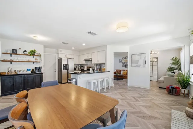 a living room with stainless steel appliances furniture and kitchen view