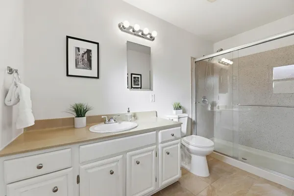a bathroom with a granite countertop sink a toilet and shower