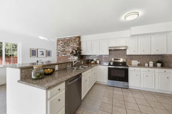 a kitchen with granite countertop a sink a stove and cabinets