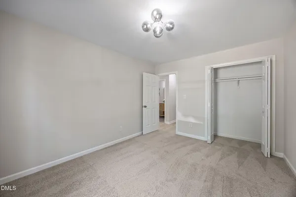 a view of an empty room with a chandelier fan