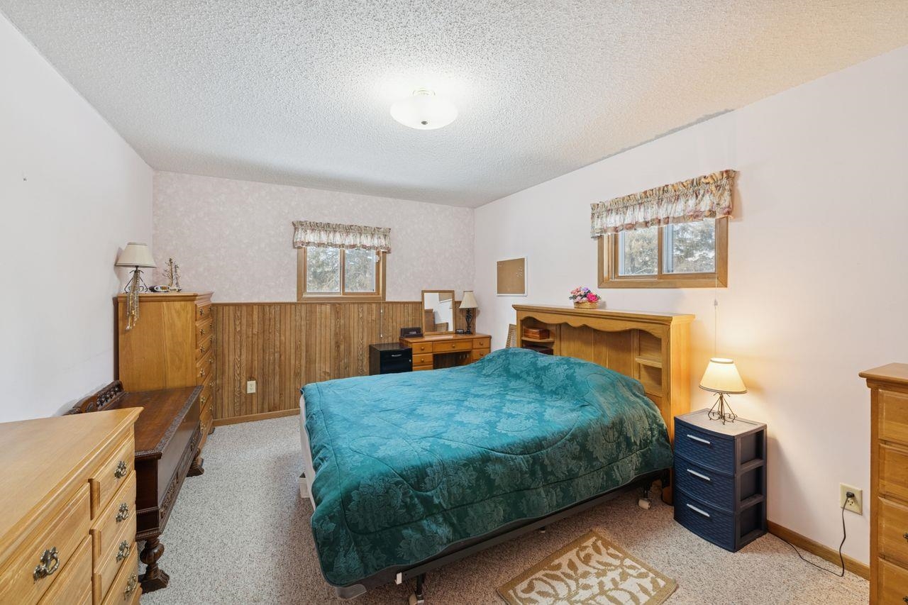 65915 Selke Road Mason, WI 54856 - Photo 12 of 33 Carpeted bedroom featuring a wainscoted wall, wooden walls, a textured ceiling, and wallpapered walls