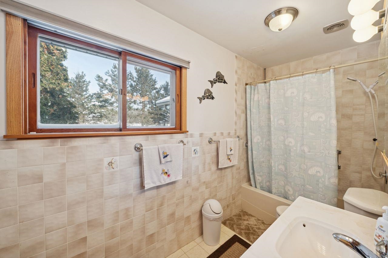 65915 Selke Road Mason, WI 54856 - Photo 15 of 33 Bathroom with tile patterned floors, shower / bath combo, tile walls, and vanity