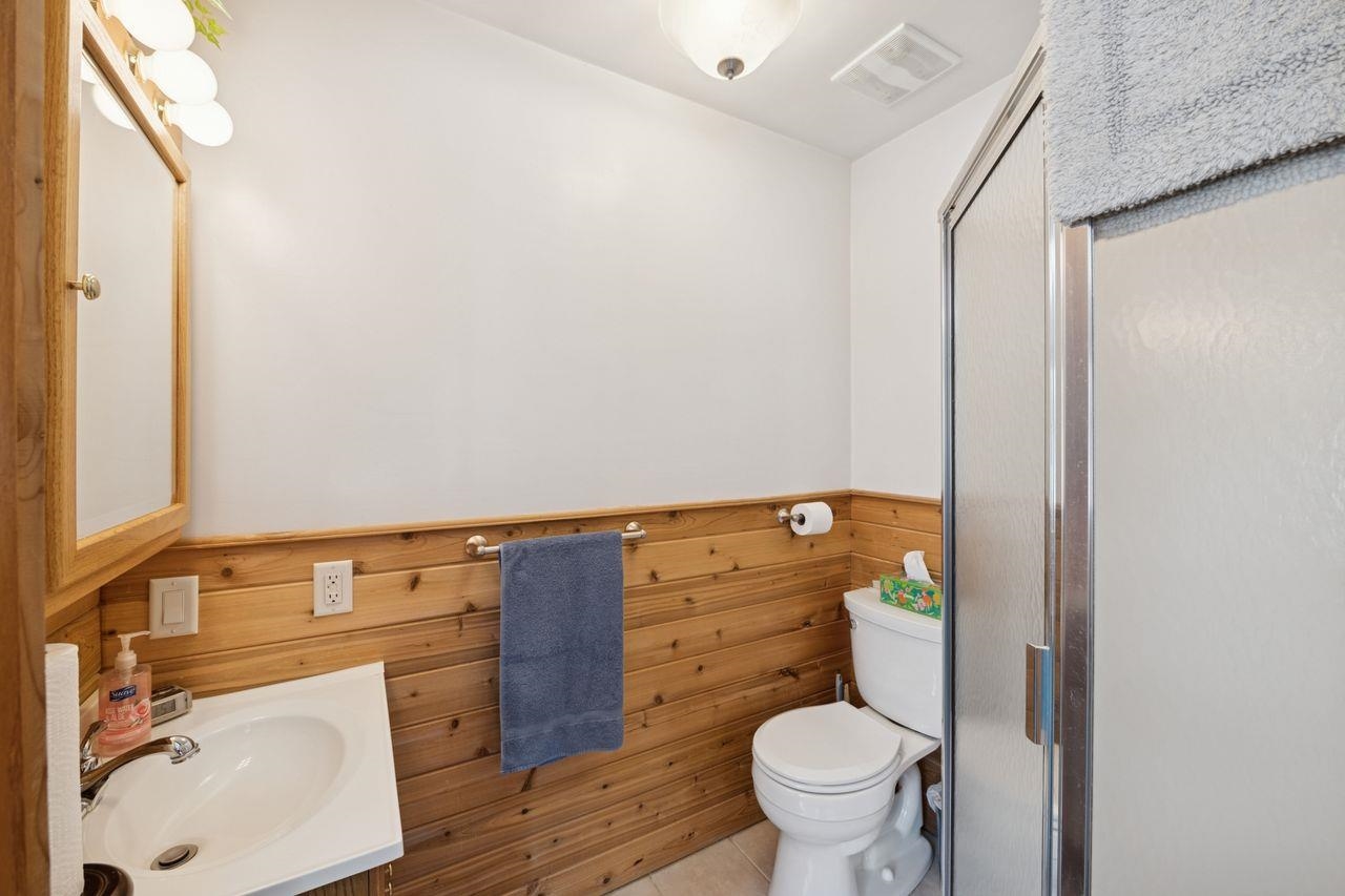 65915 Selke Road Mason, WI 54856 - Photo 17 of 33 Bathroom featuring vanity, a shower stall, a wainscoted wall, tile patterned flooring, and wood walls