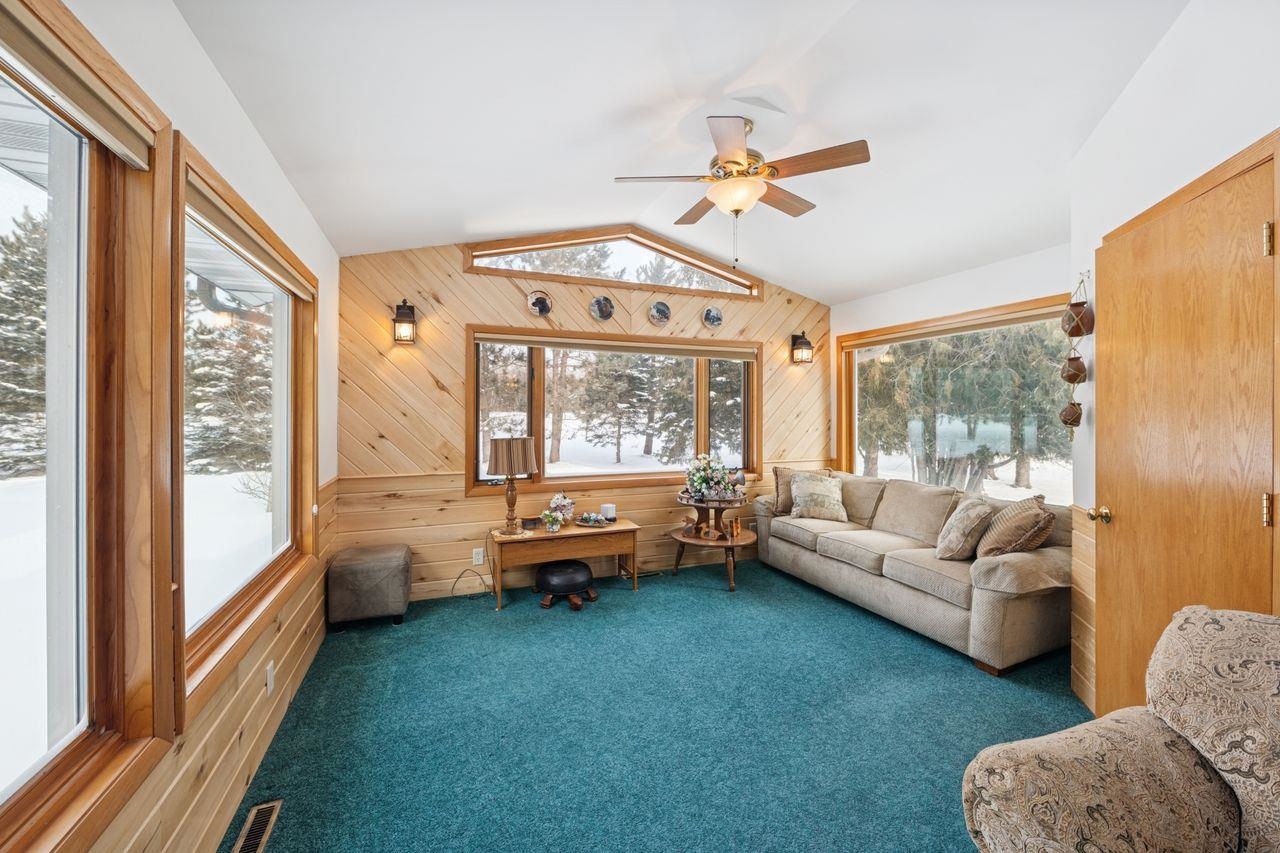 65915 Selke Road Mason, WI 54856 - Photo 4 of 33 Living room featuring carpet, lofted ceiling, ceiling fan, and wood walls