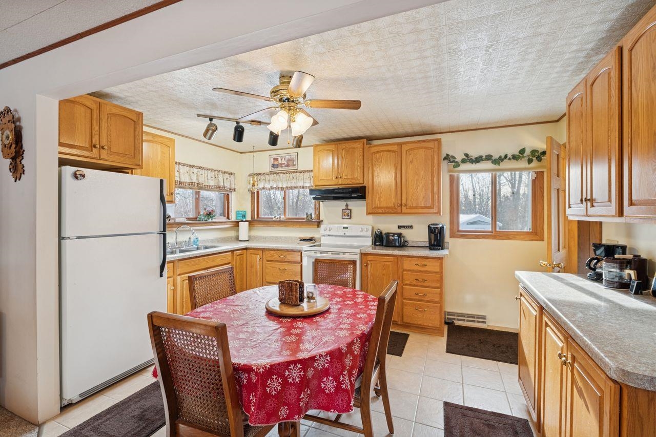 65915 Selke Road Mason, WI 54856 - Photo 7 of 33 Kitchen with white appliances, ornamental molding, light countertops, brown cabinetry, and under cabinet range hood