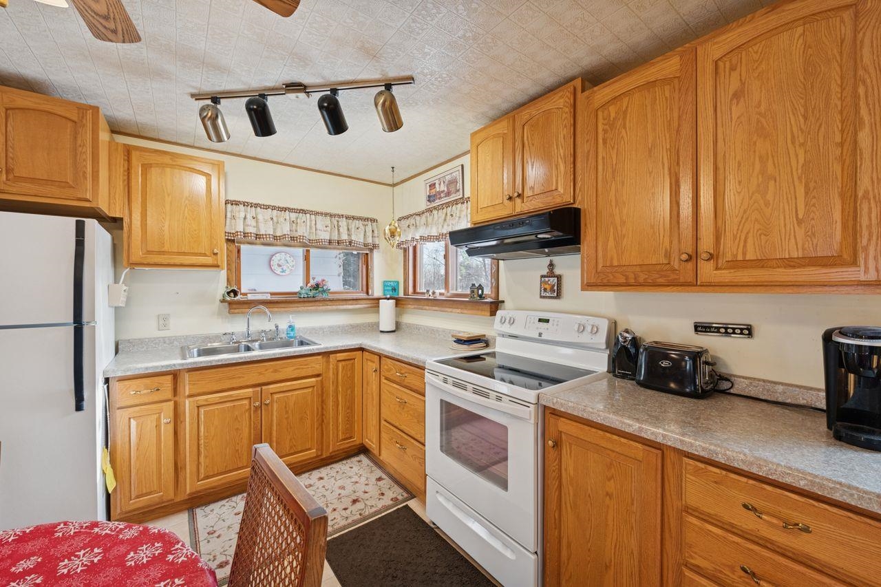 65915 Selke Road Mason, WI 54856 - Photo 8 of 33 Kitchen featuring white appliances, under cabinet range hood, brown cabinets, light countertops, and an ornate ceiling