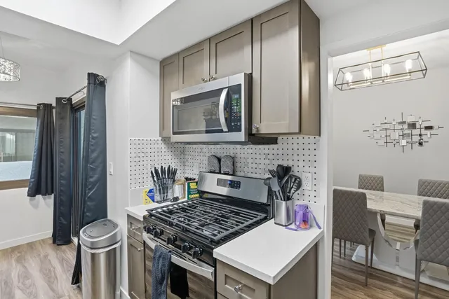 a kitchen with stainless steel appliances a stove a refrigerator a sink a table and chairs