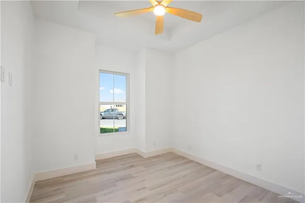 an empty room with wooden floor chandelier fan and windows