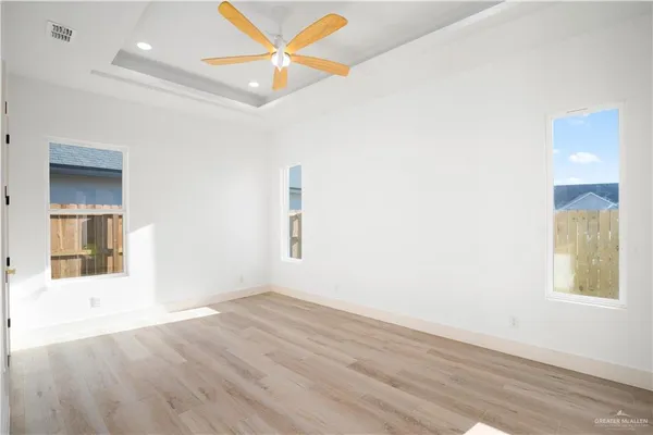 an empty room with wooden floor and windows