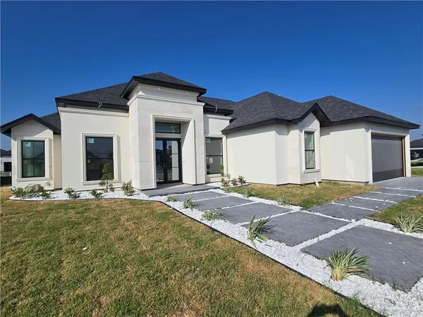 a view of a house with a yard and large tree