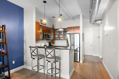 a kitchen with stainless steel appliances kitchen island granite countertop a refrigerator a stove a microwave oven a sink with island and chairs