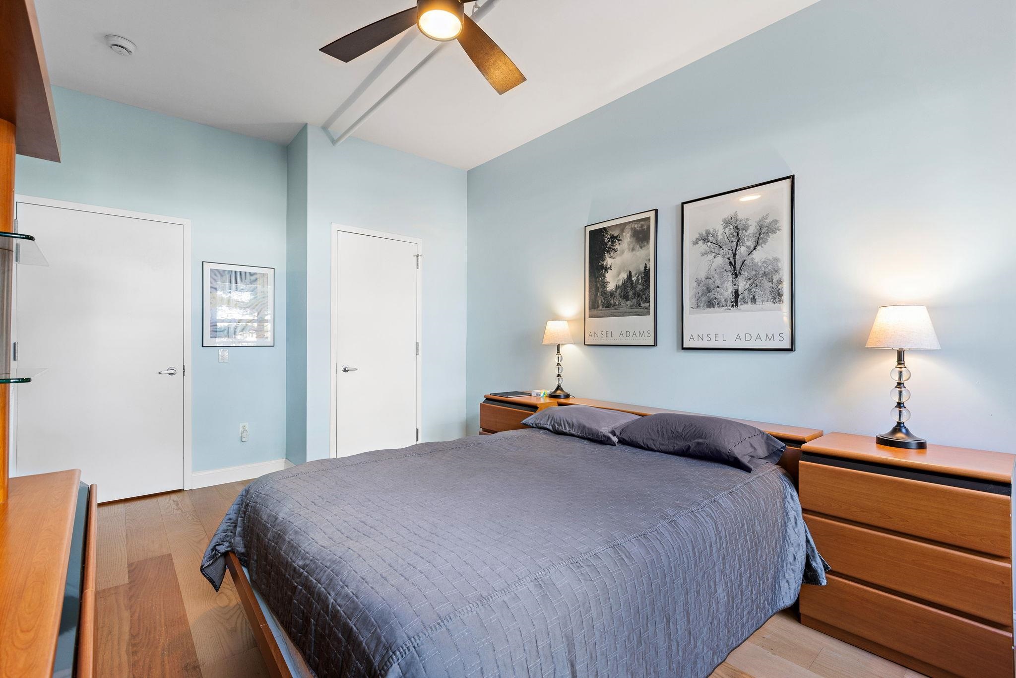 234 10th Street, Unit 306 Jersey City, NJ 07302 - Photo 7 of 15 a bedroom with a bed and a lamp on dresser