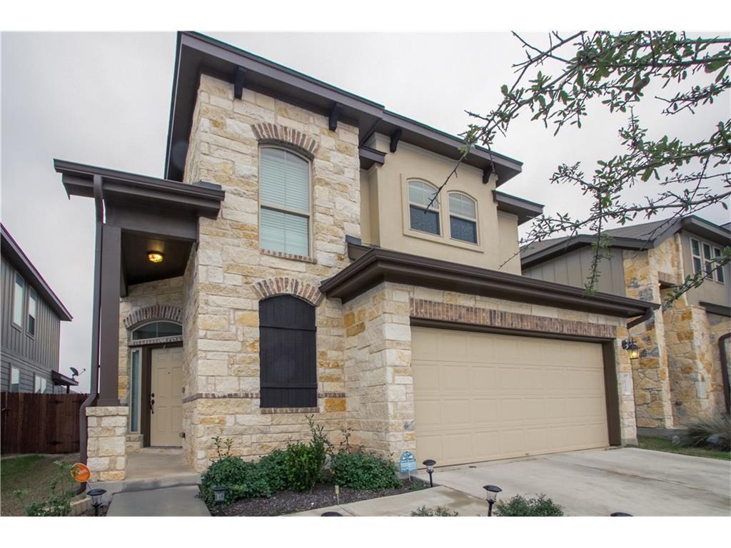 View of front facade with stone siding, driveway, a garage, and stucco siding