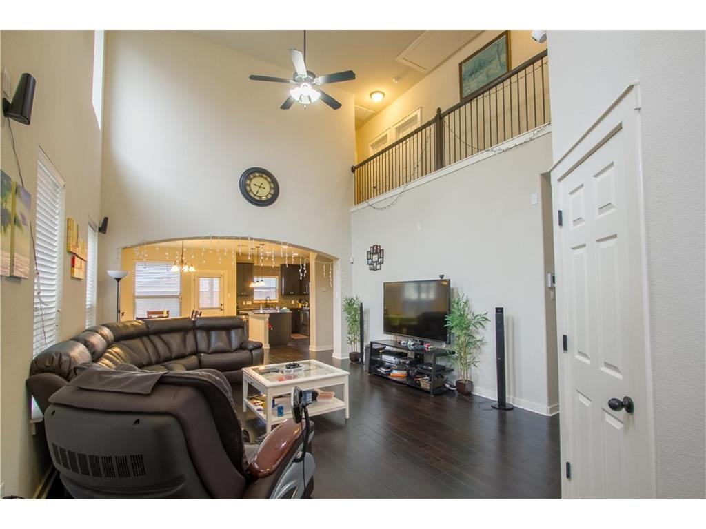 16309 McAloon Way Austin, TX 78728 - Photo 3 of 16 Living room featuring a towering ceiling, a ceiling fan, dark wood-style flooring, arched walkways, and a chandelier