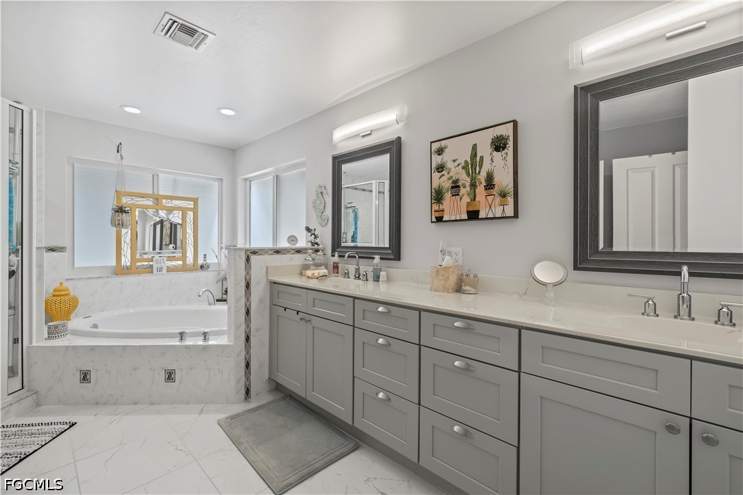 485 Peachtree Road Sanibel, FL 33957 - Photo 11 of 24 a bathroom with double vanity sink a mirror a lamp a window and a bathtub