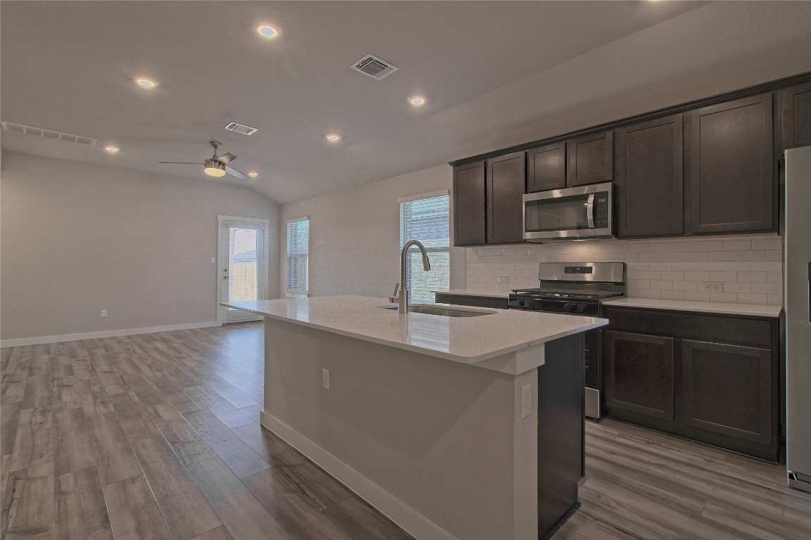 112 Halford Road Georgetown, TX 78633 - Photo 12 of 37 Kitchen with recessed lighting, light wood-style floors, appliances with stainless steel finishes, dark brown cabinets, and an island with sink