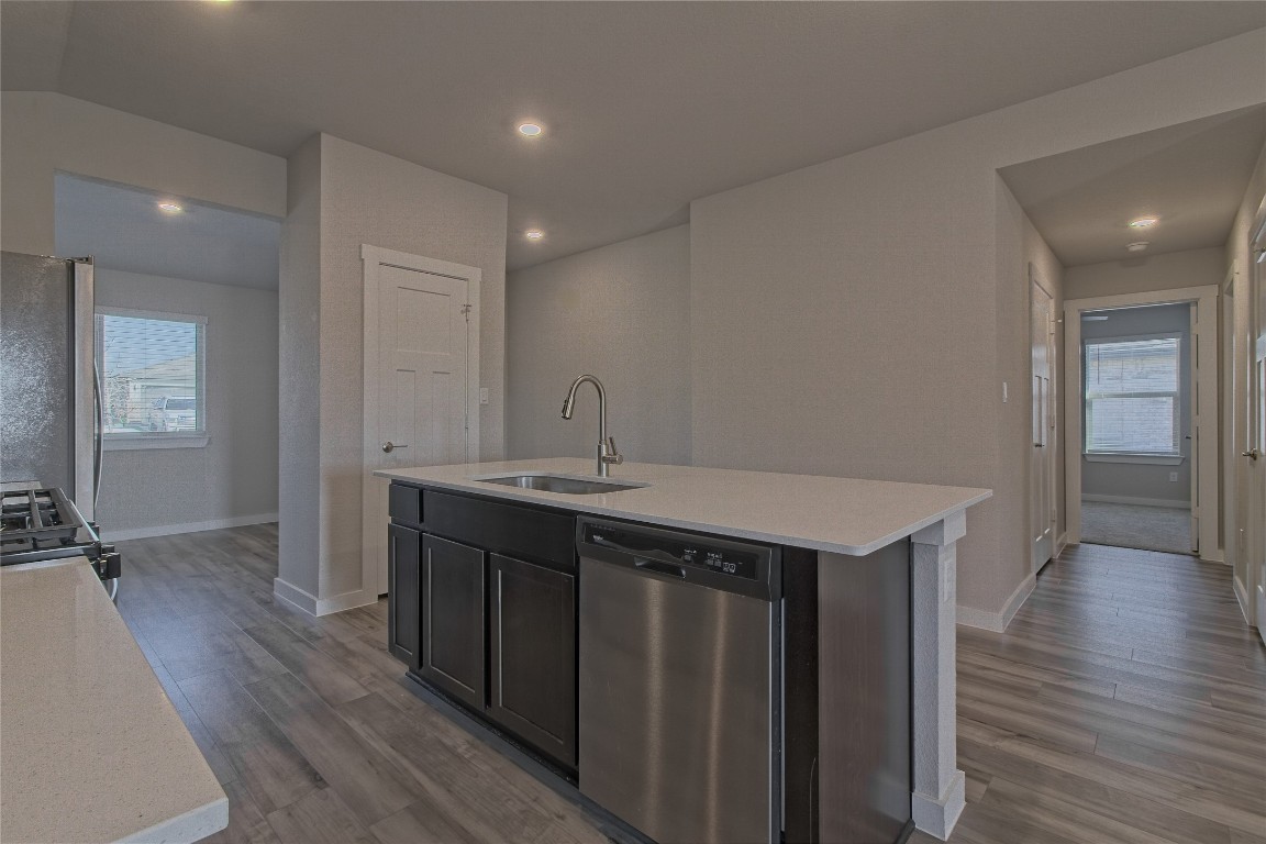 112 Halford Road Georgetown, TX 78633 - Photo 13 of 37 Kitchen featuring appliances with stainless steel finishes, light wood-style floors, an island with sink, light stone counters, and recessed lighting