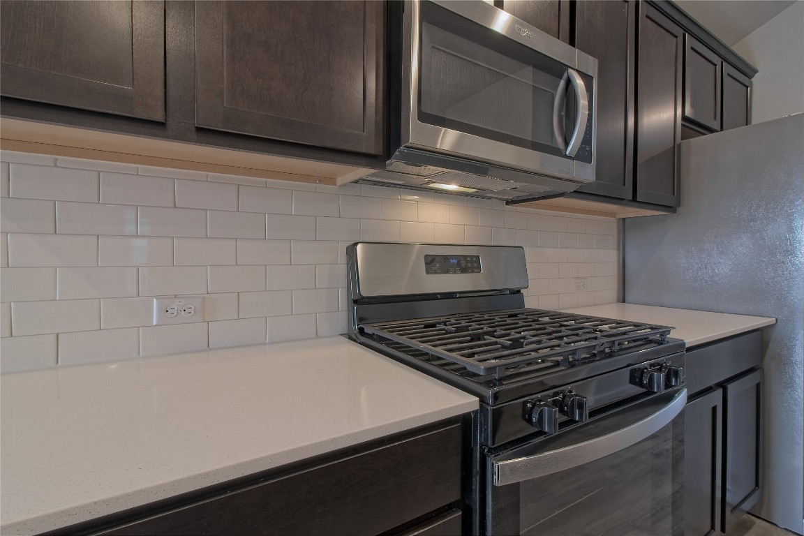 112 Halford Road Georgetown, TX 78633 - Photo 14 of 37 Kitchen with stainless steel appliances, dark brown cabinetry, tasteful backsplash, and light stone counters