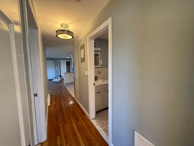 a view of a hallway with wooden floor and a bathroom