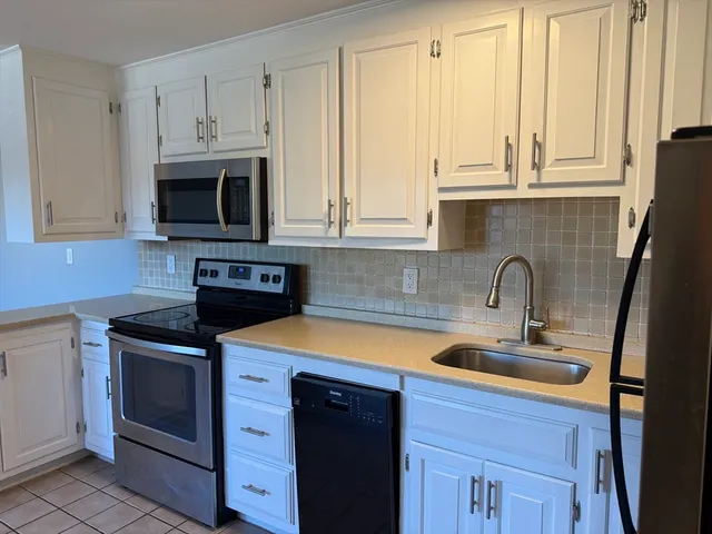 a kitchen with stainless steel appliances granite countertop white cabinets a sink and a oven